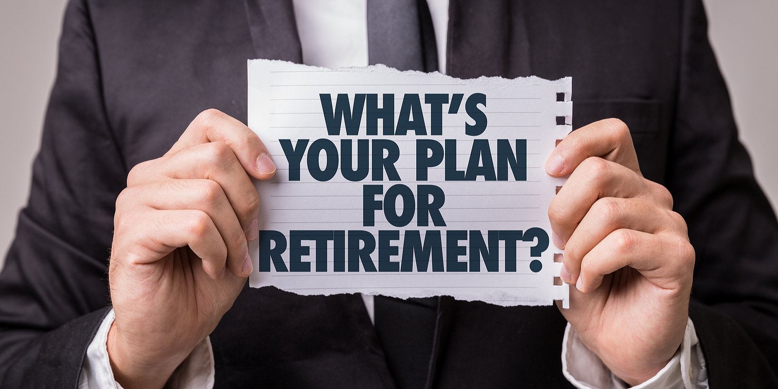 A man wearing black suit holding a paper that read Whats Your Plan for Retirement.Consider Retirement Plan Consulting