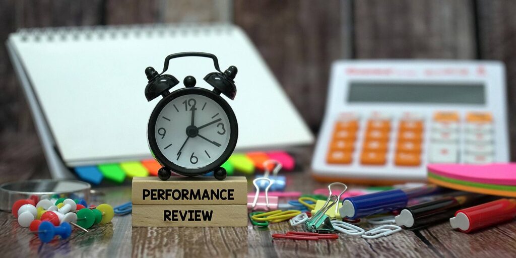 Stationery items and wooden blocks that has Performance Review written on it. A concept of Performance appraisals