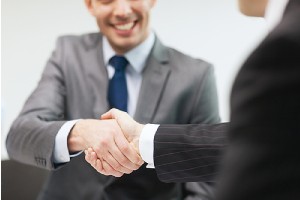 Two coworkers shaking hands in office. Choose the best retirement plan for your business