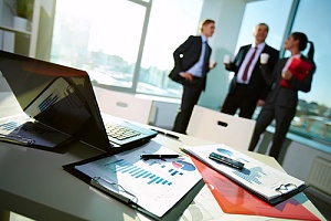 Industry information on desk with business workers talking in background 